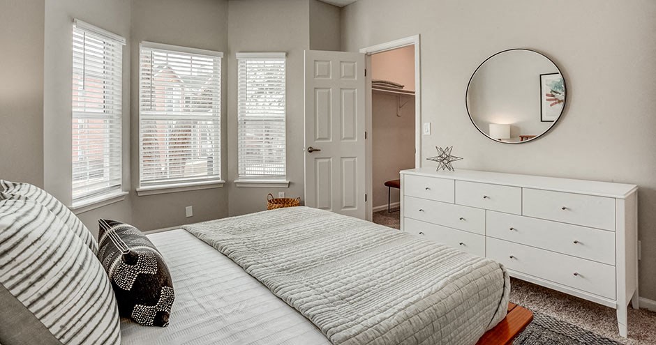 a white bedroom with a bed and a mirror