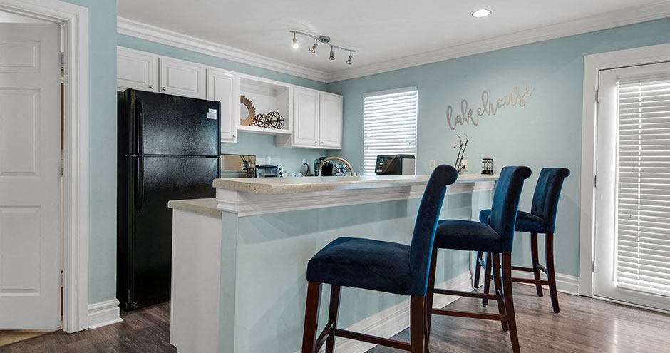 a kitchen with a bar with blue chairs and a black refrigerator