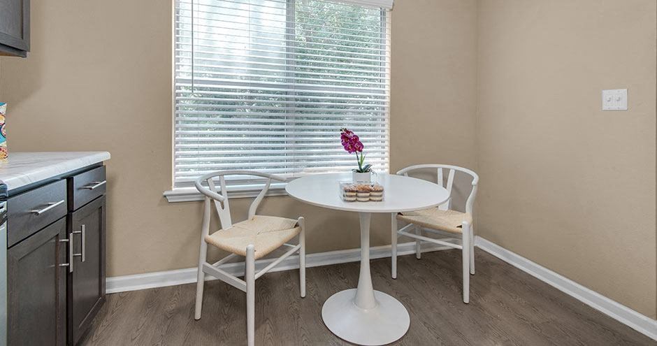 a small table and chairs in a kitchen with a window