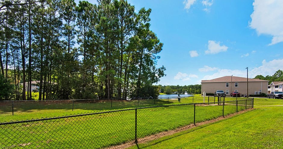 a tennis court with a fence in front of a house