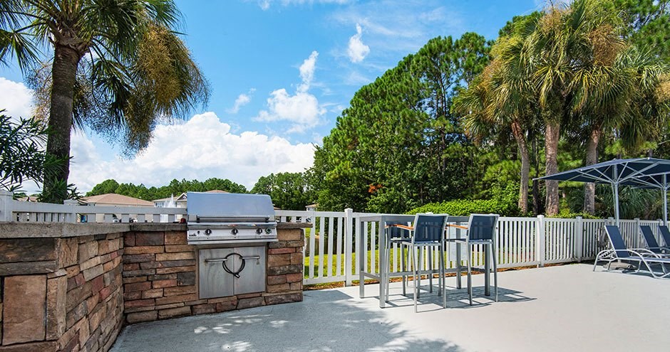 a patio with a barbecue grill and tables and chairs