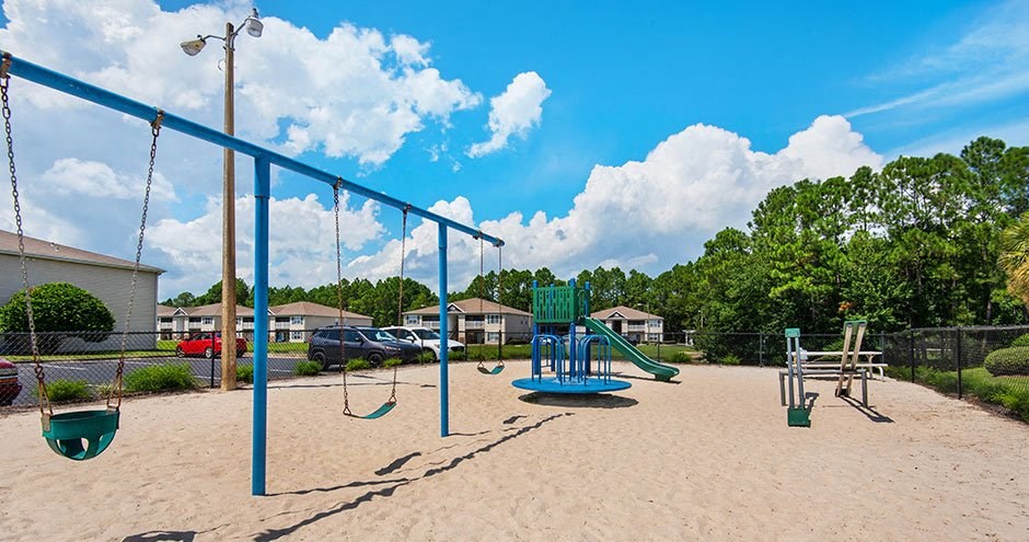 a playground with swings and a swing set on the sand
