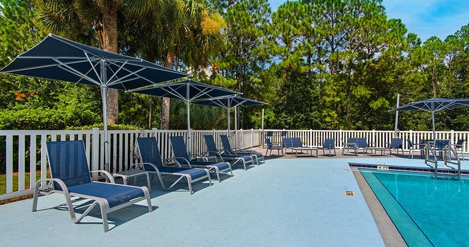 a pool with blue lounge chairs and umbrellas next to it