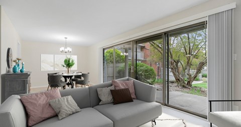 A living room with a grey couch and a dining table with chairs.