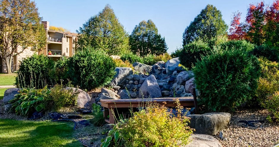 a garden with rocks and a wooden bench