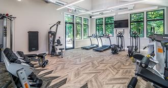 a gym with cardio machines and weights on a wooden floor
