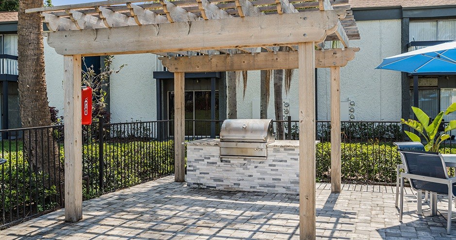 a wood pergola with a grill in front of a building
