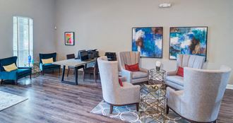 a living room with chairs and a table with a computer
