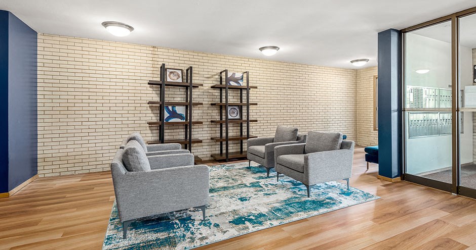a living room with chairs and a rug and a brick wall