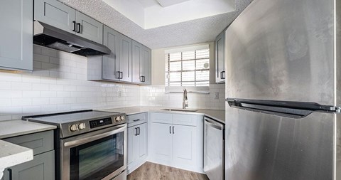 A kitchen with a stove top oven, a refrigerator, and a sink.