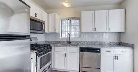 A kitchen with white cabinets and a granite countertop.