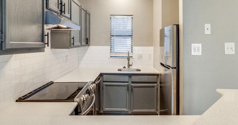 A modern kitchen with a stainless steel refrigerator and a double sink.