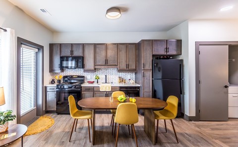 A kitchen with a table and chairs in the foreground and a refrigerator in the background.
