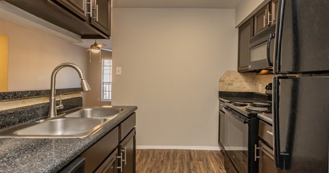 A kitchen with a black fridge and a stove top oven.