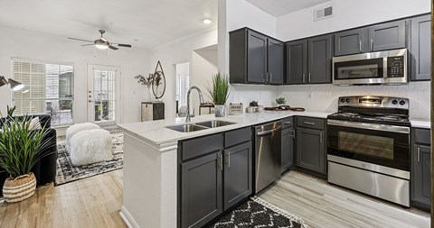 A modern kitchen with dark cabinets and stainless steel appliances.