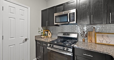 A kitchen with black cabinets and a white door.