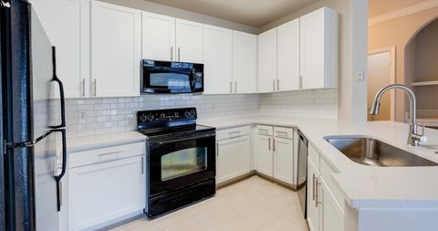 A kitchen with black appliances and white cabinets.