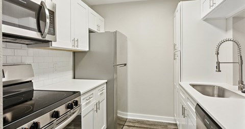 A kitchen with white cabinets and appliances.