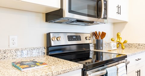 A modern kitchen with a black stove top oven and a microwave above it.