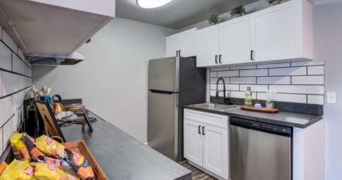 A kitchen with a stainless steel refrigerator and black dishwasher.