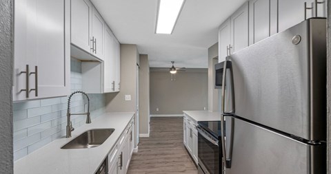 A modern kitchen with a stainless steel refrigerator and a sink.