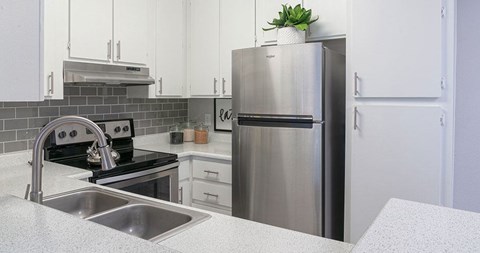 A modern kitchen with a stainless steel refrigerator and a black stove top.