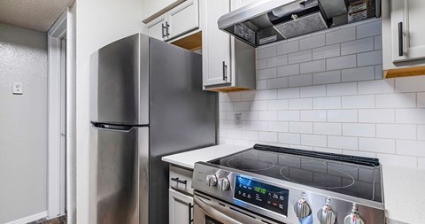 A modern kitchen with a stainless steel refrigerator and an oven with a digital display.
