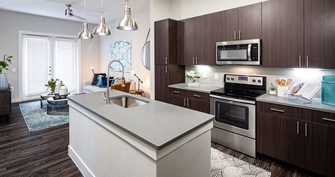 A modern kitchen with dark wood cabinets and stainless steel appliances.