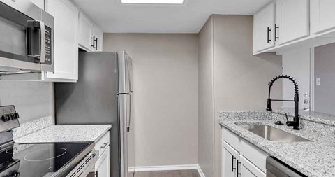 A kitchen with white cabinets and a granite countertop.