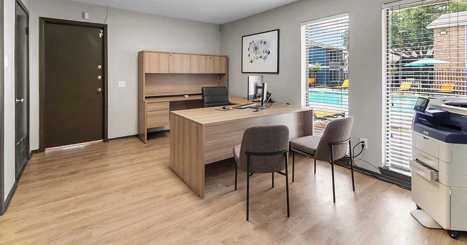 a room with a desk and chairs and a window