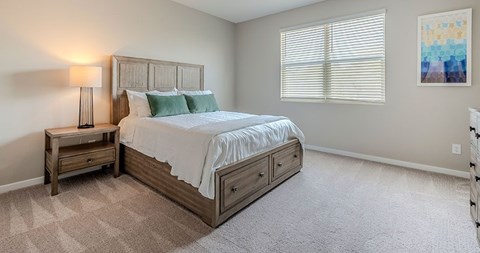 A bedroom with a large bed and a nightstand with a lamp.