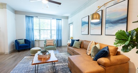 A living room with a brown leather couch, a blue sofa, and a coffee table with a plant on it.
