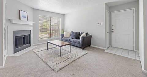 A living room with a grey couch and a fireplace.
