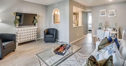 A living room with a grey sofa and a glass coffee table.