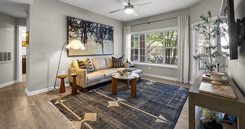 A living room with a white sofa and a large abstract painting on the wall.