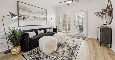 A living room with a black couch, a rug, and a large painting on the wall.