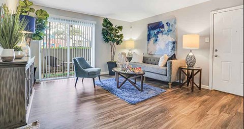 A living room with a grey couch, a blue rug, and a painting on the wall.