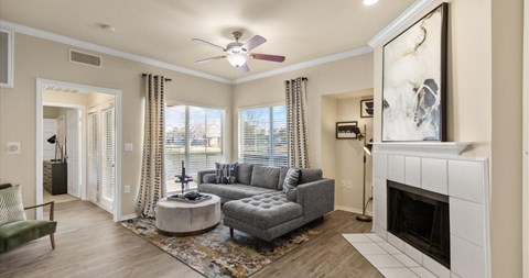 A living room with a grey couch and a fireplace.