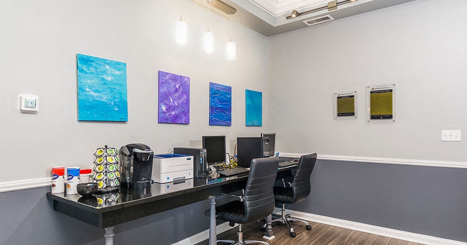 an office with two desks and two chairs and three computer monitors