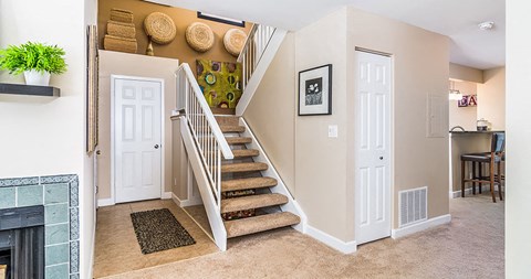 a living room with a staircase and a fireplace