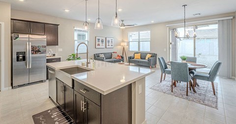 A modern kitchen with a large island and a dining area with chairs.