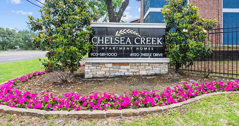 a sign in front of a building with pink flowers