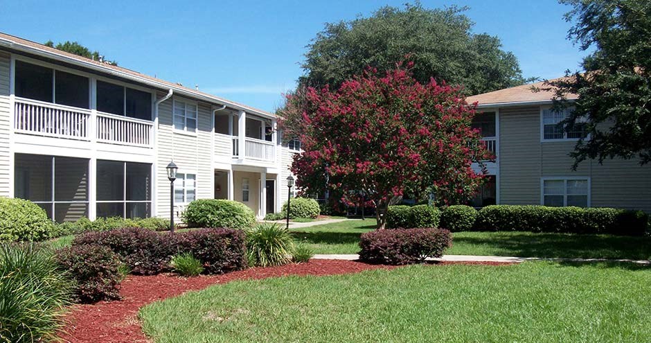 a white apartment building with a lawn and trees