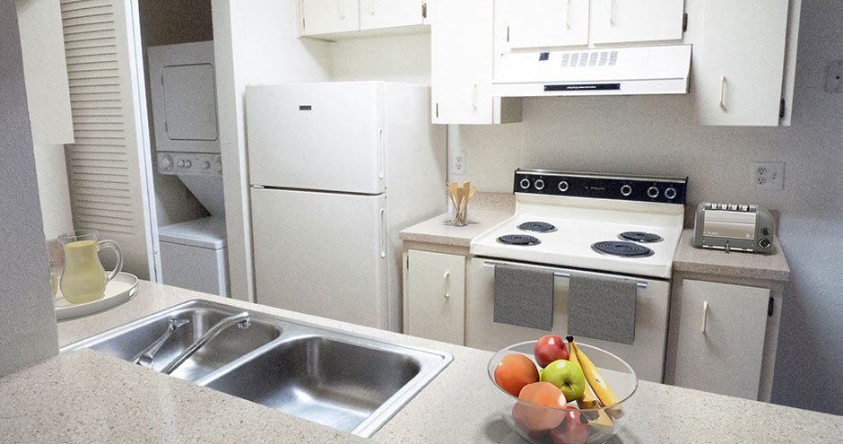 a kitchen with white appliances and a bowl of fruit
