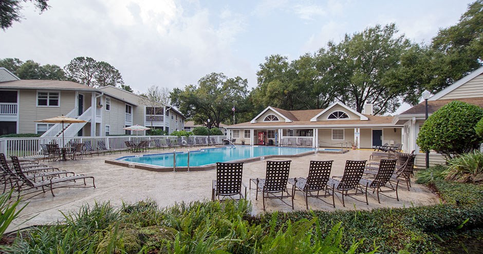 a swimming pool with chairs and houses in the background
