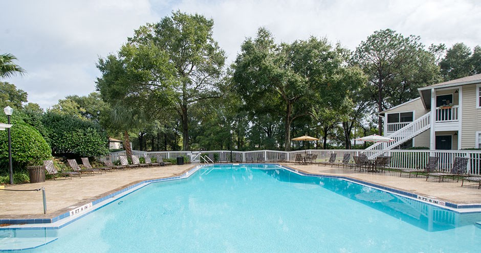 a swimming pool with a house and trees in the background