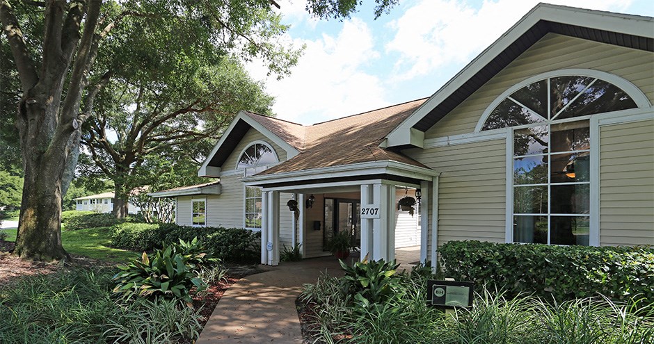 the front of a house with a walkway and a tree
