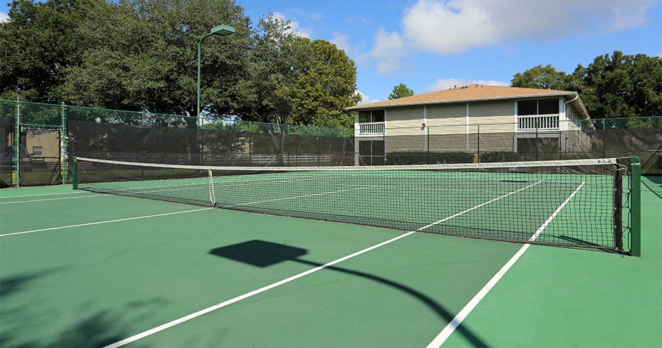 a tennis court with a house on the other side of it