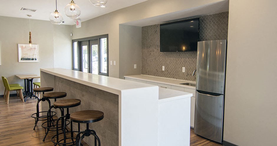 a kitchen with a bar with stools and a refrigerator