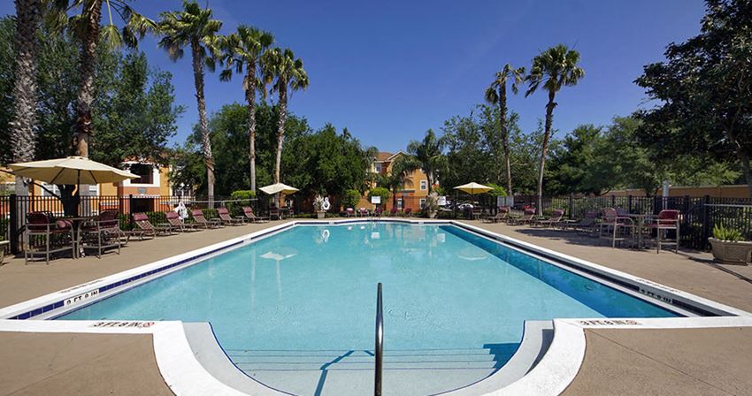 a swimming pool with chairs and umbrellas around it